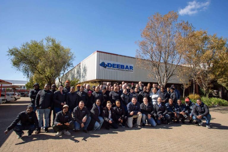 Group photo of Deebar team in front of a building with the Deebar logo.