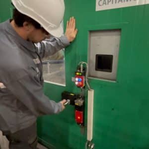 Worker using Fortress interlock actuator handle mounted to a green machine enclosure.