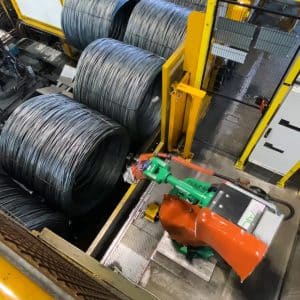 Inside view of robot arm interacting with large steel wire coils behind yellow guarding with amGardpro.