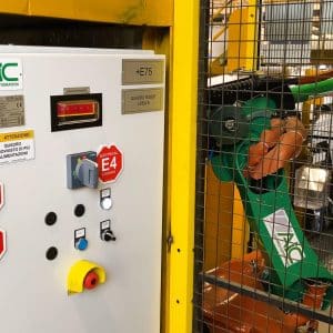 Green robot arm visible through yellow guarding with nearby control panel.